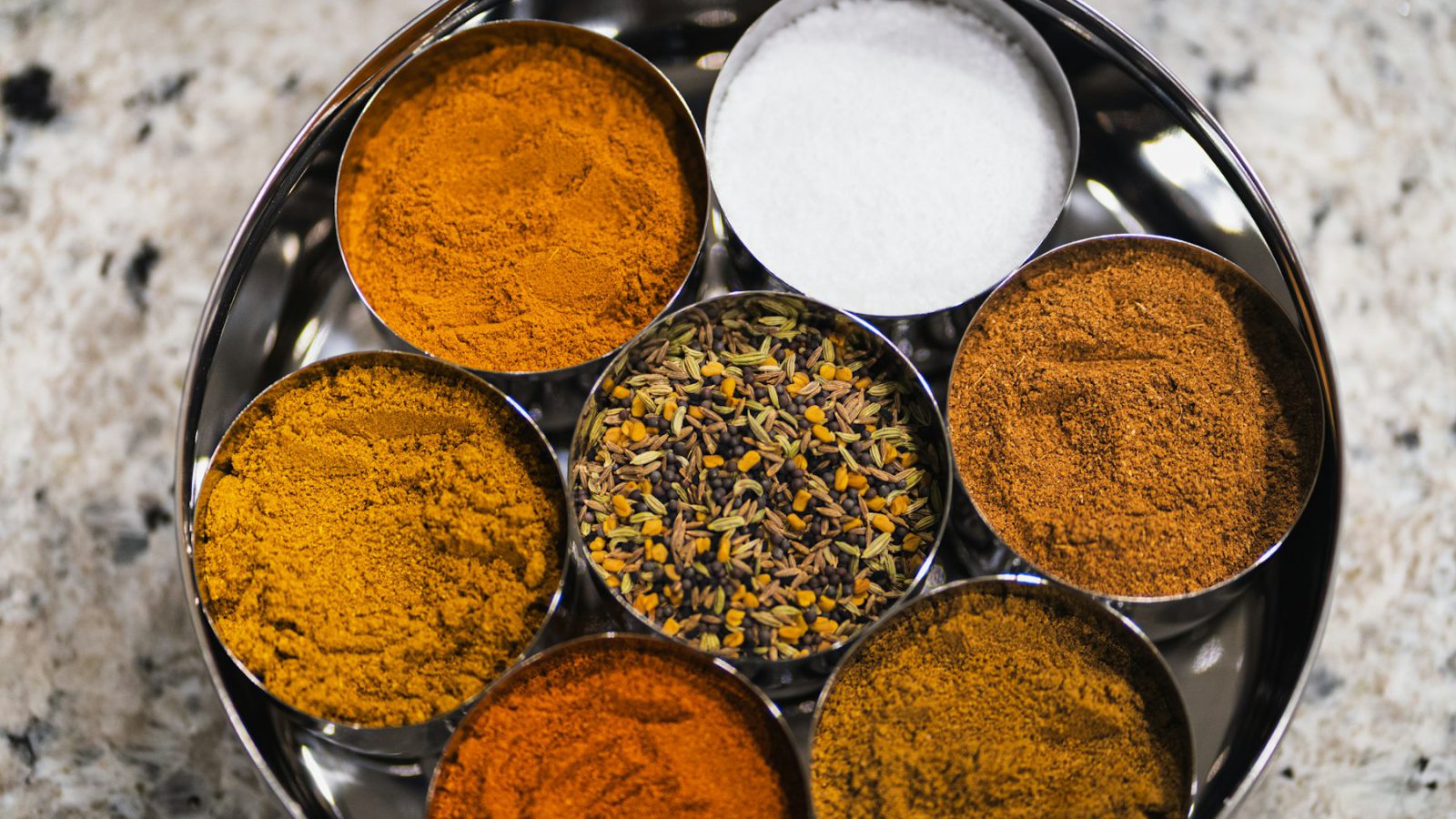 Indian spices in metal bowls on a tray