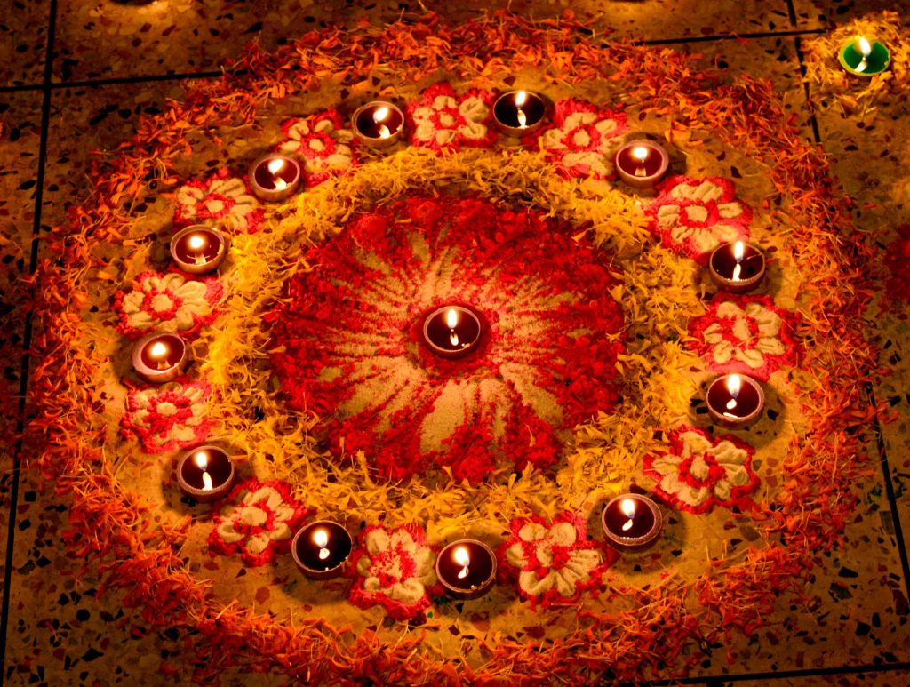 Rangoli surrounded by lit diyas